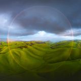 Weite grüne, hügelige Landschaft mit Wolken am Horizont