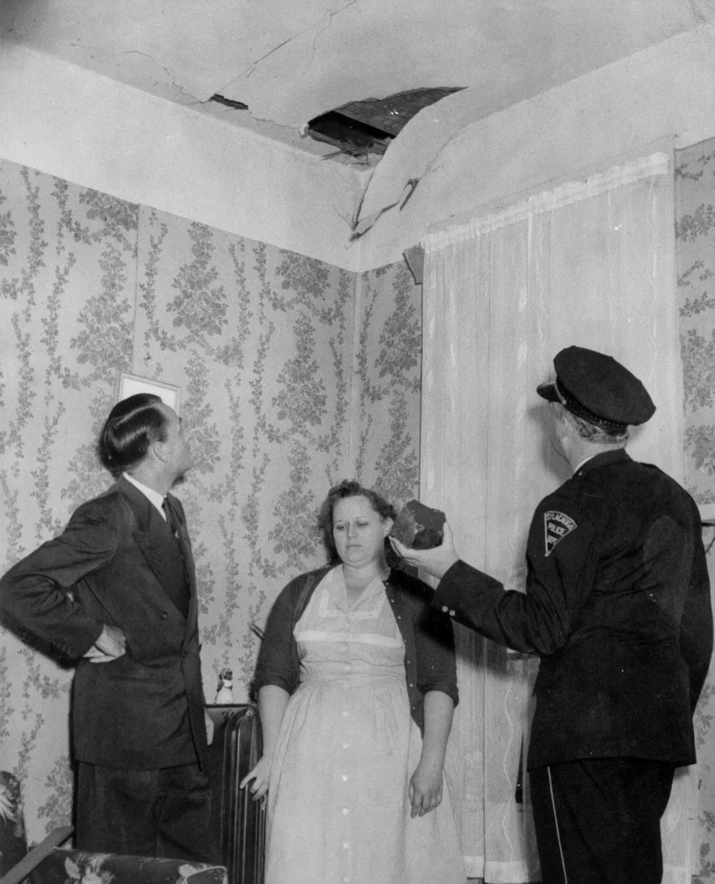 Ann Hodges, ihr Mann (l.) und ein Polizist begutachten am 30. November 1954 das Loch in der Hausdecke, das der Meteorit geschlagen hat, den der Beamte in der Hand hält 