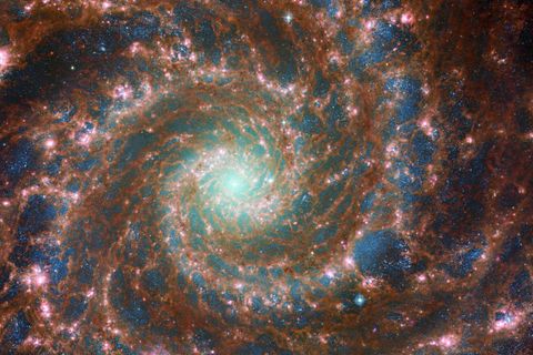 An der Spiralgalaxie Messier 74 zeigt sich eindrucksvoll, wie ungleichmäßig interstellare Materie in Galaxien verteilt ist. Manche Gebiete sind fast frei von ihr (dunkle Blasen mit bläulichen Sternen), dazwischen knubbeln sich Gas und Staub (rötlich leuchtend): Dort entstehen neue Sterne (pink)