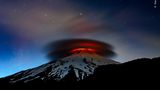 Die Lava des Vulkans Villarrica beleuchtet eine kreisförmige, zweischichtige Wolke die, die Spitze  Vulkans umhüllt.