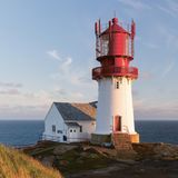 Leuchtturm mit roter Spitze, im Hintergrund das offene Meer