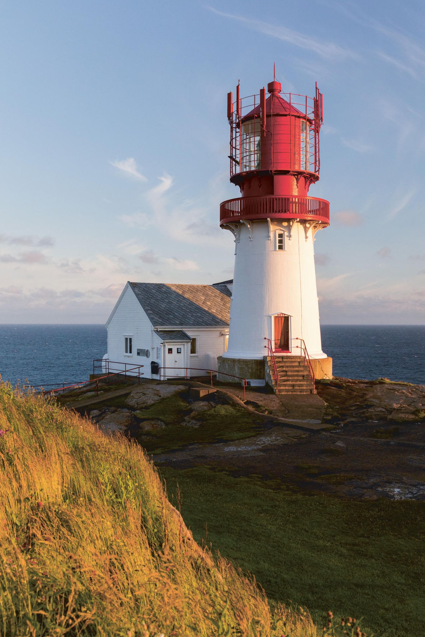 Leuchtturm mit roter Spitze, im Hintergrund das offene Meer