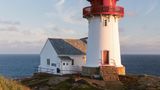 Leuchtturm mit roter Spitze, im Hintergrund das offene Meer