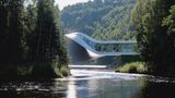 Ein Ausschnitt der geschwungenen Architektur des Museums umgeben von Wald