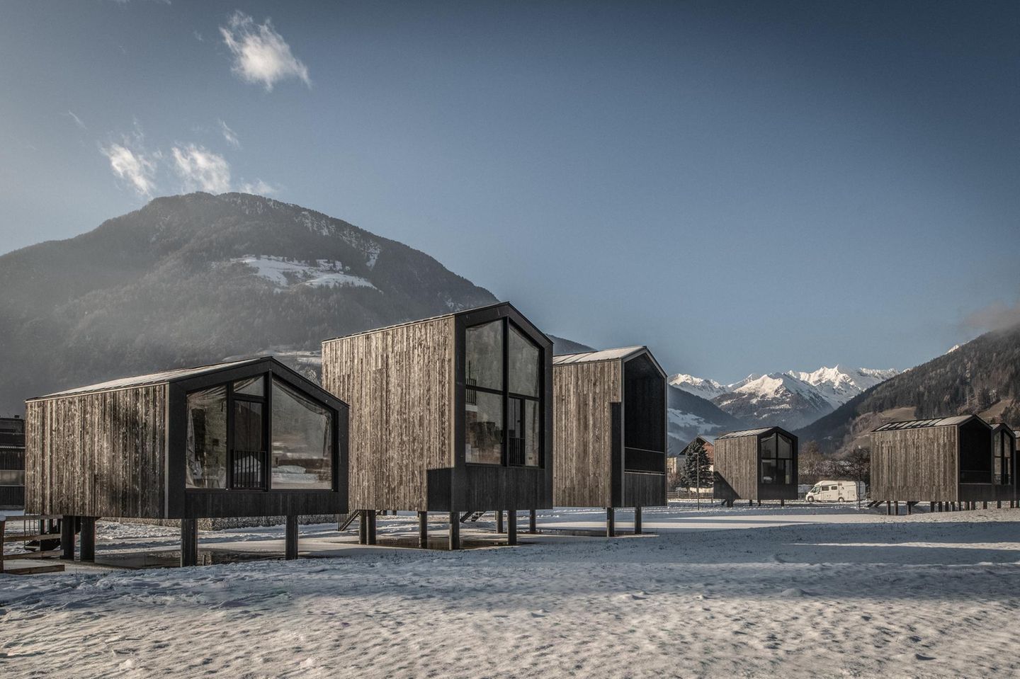 Von Chalet bis Luxushotel Moderne Holzhütten vor verschneiter Bergkulisse