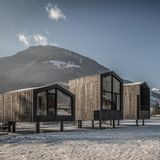 Moderne Holzhütten vor verschneiter Bergkulisse