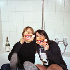 Ausgelassene Freundinnen posieren in Badewann für ein quatschiges Foto.