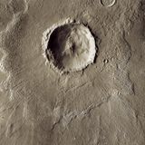 Unzählige Krater prägen die Marsoberfläche. Dieser Impakt zerschmetterte den Asteroiden sowie die Marsoberfläche, ein tiefer Krater bildete sich. Doch in seiner Mitte federte die Oberfläche zurück, ein Zentralberg entstand. Das zerstobene Gestein von Asteroid und Marsoberfläche wurde nach außen geschleudert und verteilte sich um den Einschlagsort.