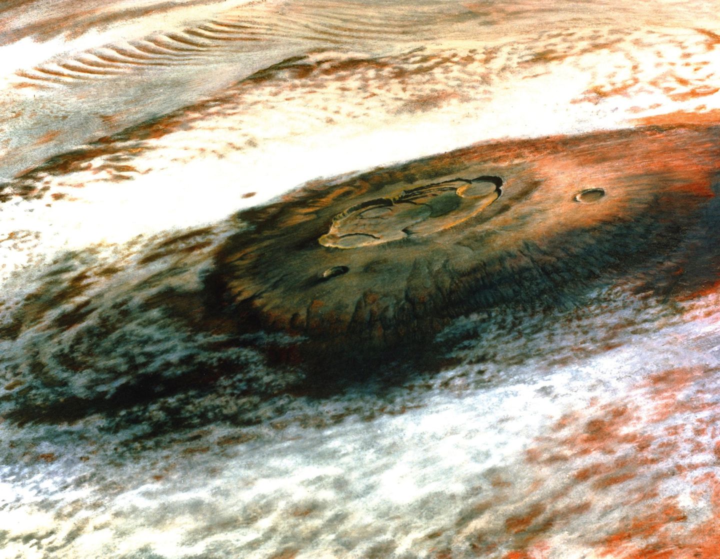 Am 31. Juli 1976 gab die NASA dem Orbiter Viking 1 den Befehl, diese Postkartenansicht des Olympus Mons aufzunehmen. Mit 22 Kilometer Höhe ist der dunkle, von Wolken umgebene Vulkan nicht nur der größte des Mars, sondern des gesamten Sonnensystems. Um das Foto für eine Fernsehübertragung geeignet zu machen, wurden Sättigung und Kontrast bis zum Äußersten getrieben.