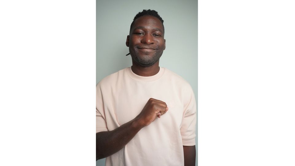 Afrofluencer Stève Hiobi (Dein Bruder Stève) Afrofluencer Stève Hiobi (Dein Bruder Stève) hält seine Faust an die Brust