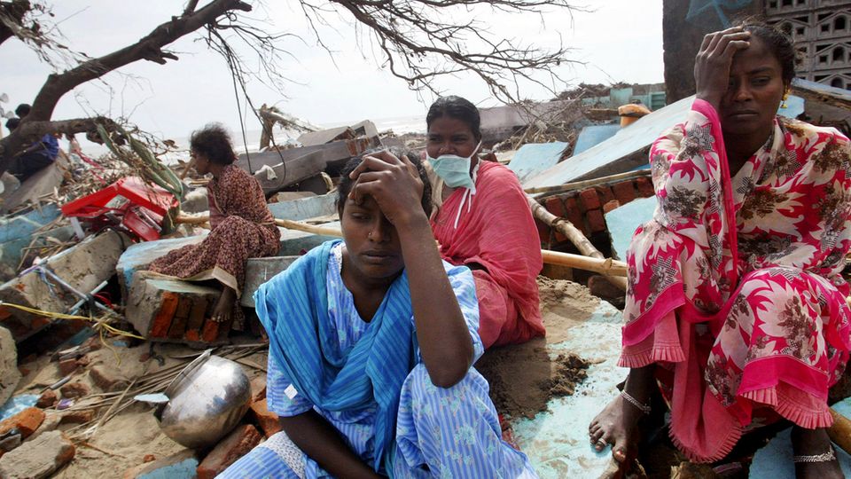 Trauernde Frauen am Strand im Südosten Indiens, um sie herum Trümmer von Häusern