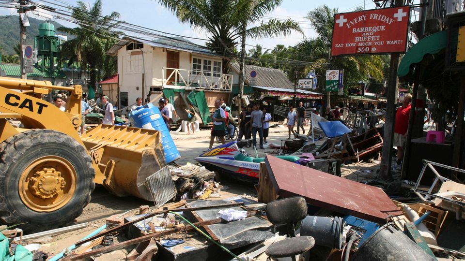 Ein gelber Bulldozer schiebt auf Phuket Trümmer vor sich her 