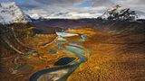 Ein Tal mit Fluss, im Hintergrund Berge