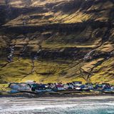 Ein kleines Dorf an der Küste mit Bergen im Hintergrund