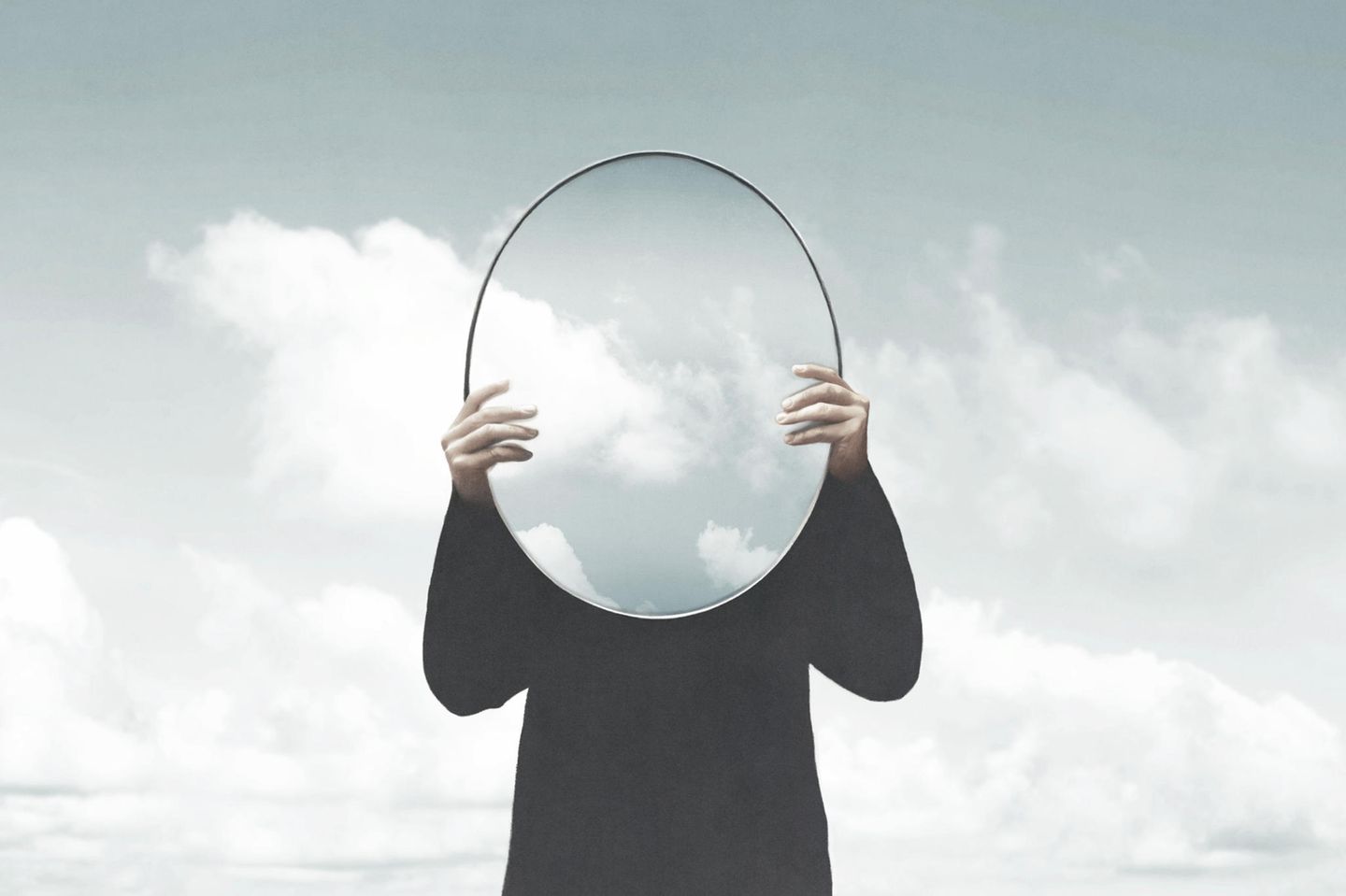 Person hält Spiegel mit Wolken vor sich