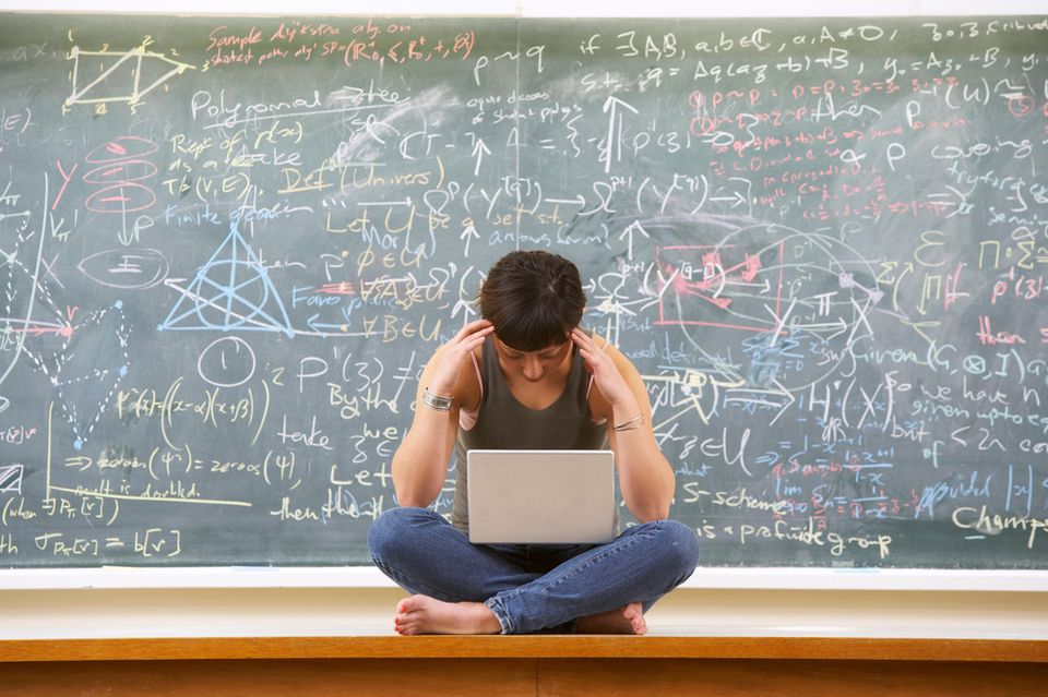 Schülerin sitzt vor großer Tafel mit Mathematikformeln und denkt 1.5341