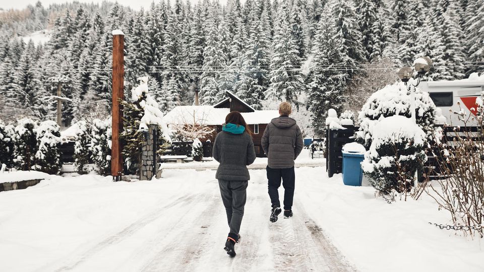 Zwei Personen gehen auf den verschneiten Campingplatz 