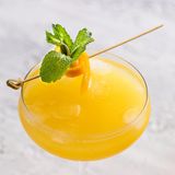 Ein, mit orange leuchtendem Aqua de Valencia, gefülltes glas. Garniert mit Orangenschale und Minzblatt, von oben fotografiert.