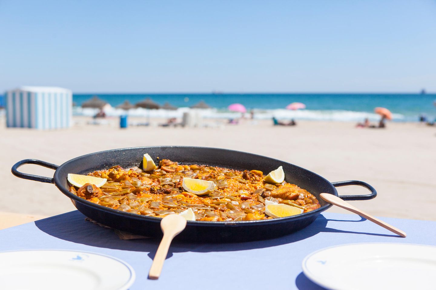 Unbedingt probieren: Paella Valenciana Ein Valencia-Besuch ohne Paella? Undenkbar! Dieses Gericht ist eng mit der Stadt verbunden. Die Paella Valenciana gilt als authentische Paella. Der Reis für das Gericht wird im Albufera-Park angebaut. Dort soll die Paella auch erfunden worden sein. Das Wort selbst stammt aus dem Valencianischen und bedeutet so viel wie "Bratpfanne". In der werden die Hauptzutaten angebraten, darunter meist Huhn und Kaninchen, Ferradura-Bohnen, Garrofó-Bohnen und Tomaten. Es gibt aber auch Varianten mit Fisch oder vegetarische mit Gemüse.