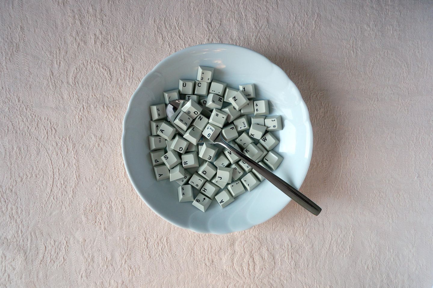 In einem Suppenteller liegen Tasten einer Computer-Tastatur und ein Löffel