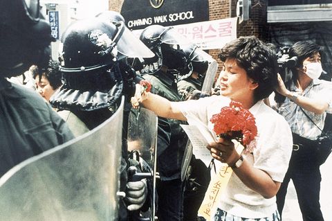 Eine Südkoreanerin übergibt einem Polizisten Blumen
