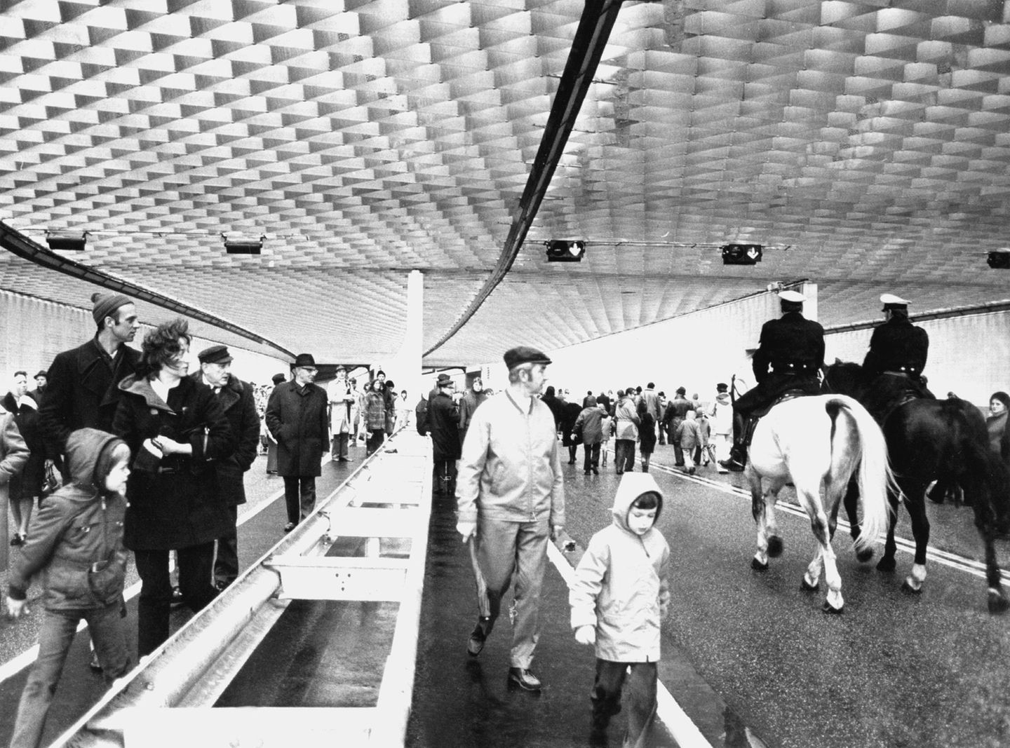 Viele Fußgänger und zwei Polizisten auf Pferden durchwandern den neu eröffneten Elbtunnel