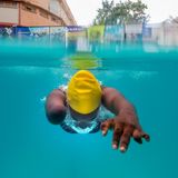 Die Leistungsschwimmerin Husnah Kukundakwe während ihres Trainings in Uganda: Elegant gleitet sie durch das türkisblaue Wasser, während sich Luftblasen um ihren Kopf sammeln. Die dynamische Aufnahme stammt von der niederländischen Dokumentarfotografin Marijn Fidder, die die 15 jährige Leistungssportlerin in ihrer Heimat in Kampala bei der Vorbereitung auf die Paralympics begleitete. 