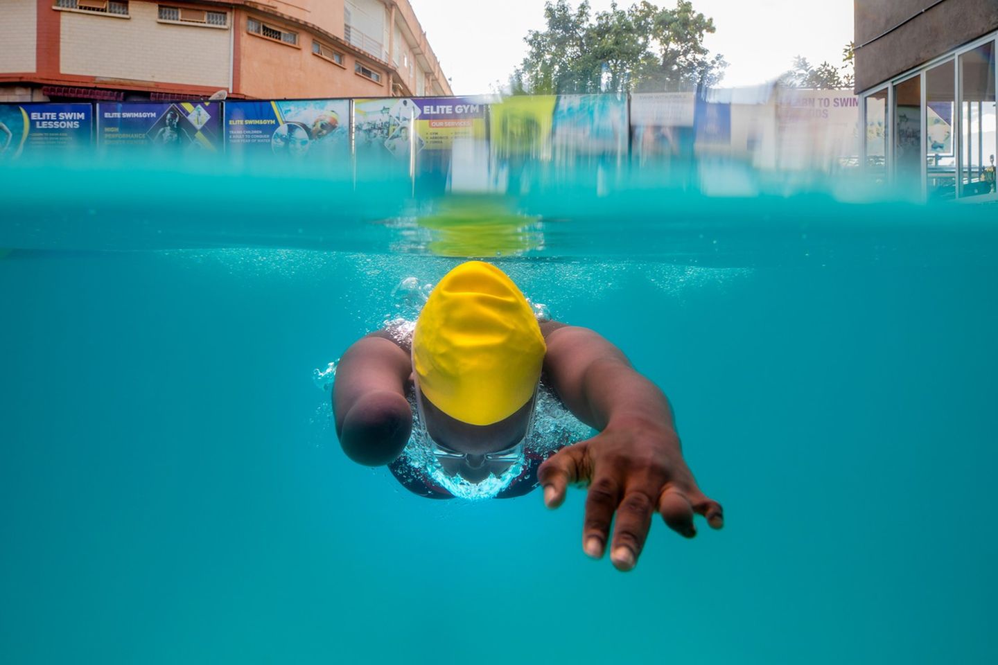 Die Leistungsschwimmerin Husnah Kukundakwe während ihres Trainings in Uganda: Elegant gleitet sie durch das türkisblaue Wasser, während sich Luftblasen um ihren Kopf sammeln. Die dynamische Aufnahme stammt von der niederländischen Dokumentarfotografin Marijn Fidder, die die 15 jährige Leistungssportlerin in ihrer Heimat in Kampala bei der Vorbereitung auf die Paralympics begleitete. 