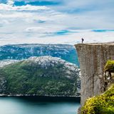 Ein Mensch steht auf der Viereckigen Felskante und blickt über die weite Landschaft.