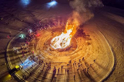 Menschen stehen um Lagerfeuer
