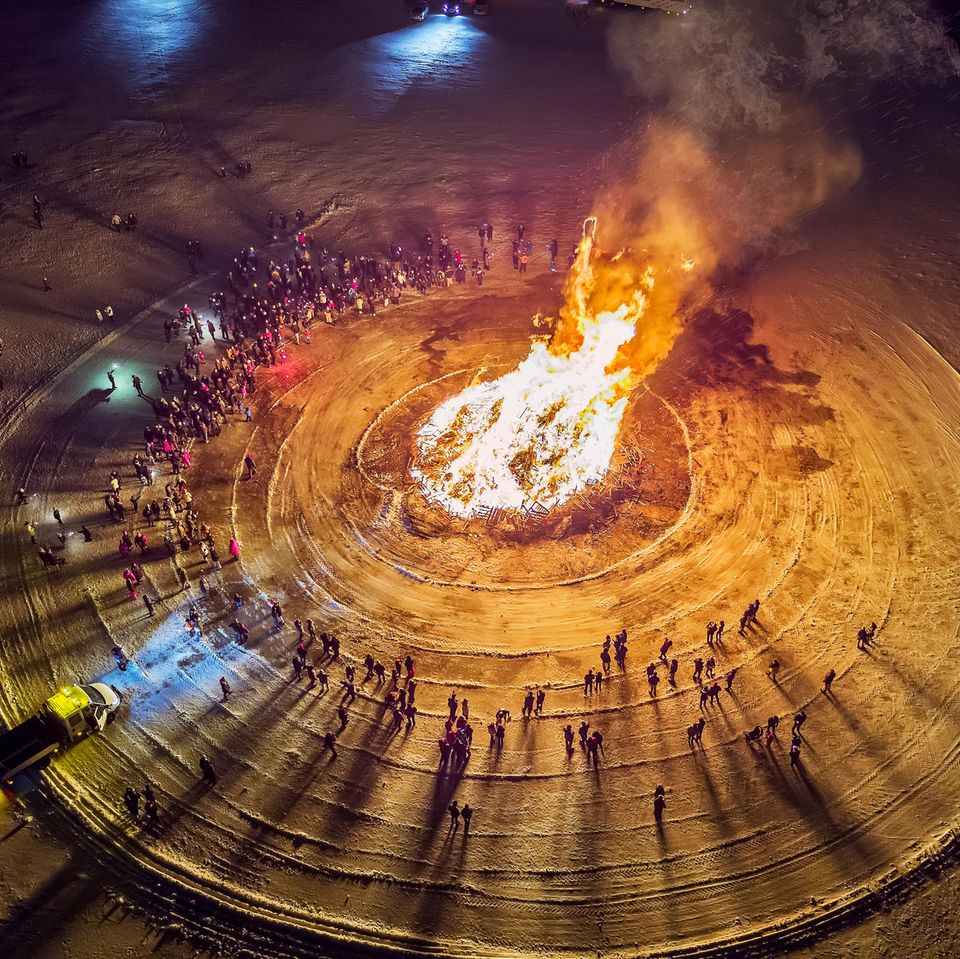 Menschen stehen um Lagerfeuer