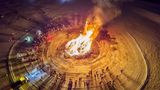 Menschen stehen um Lagerfeuer