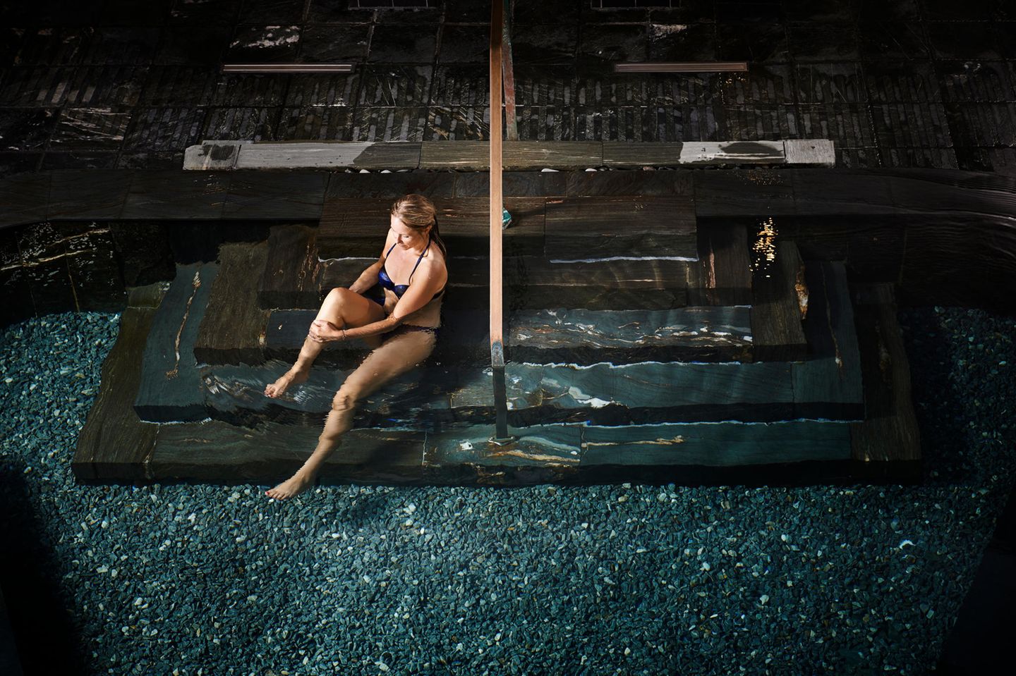 Frau sitzt auf einer Treppe am Pool im Hvidbjerg Strand Camping