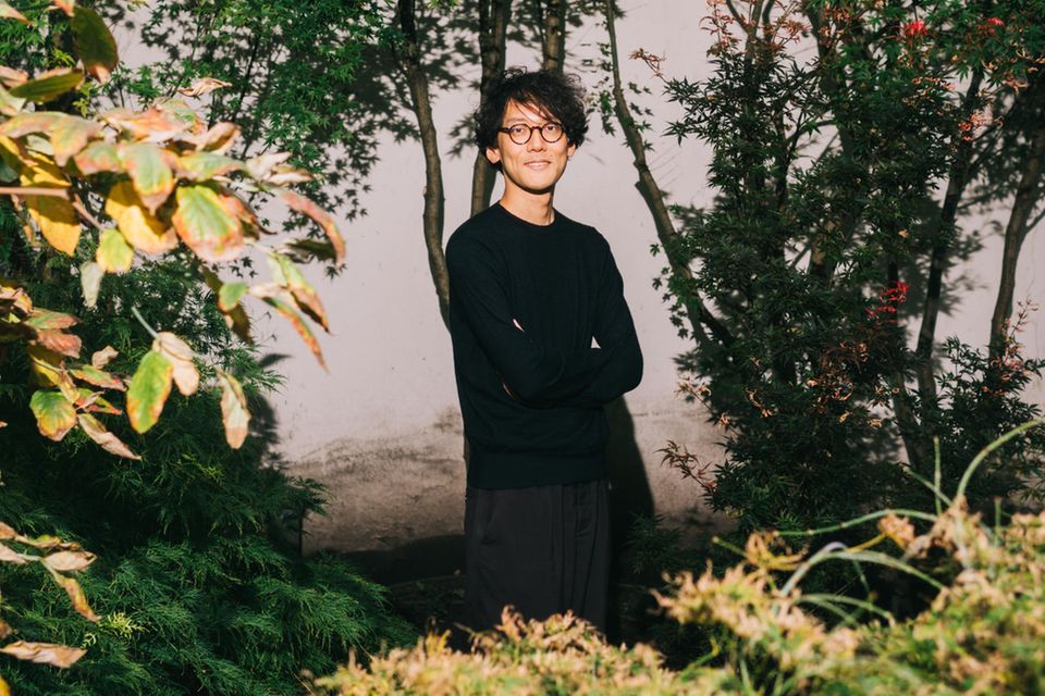 Kohai Saito steht an einen Baum gelehnt im Garten 0.6675