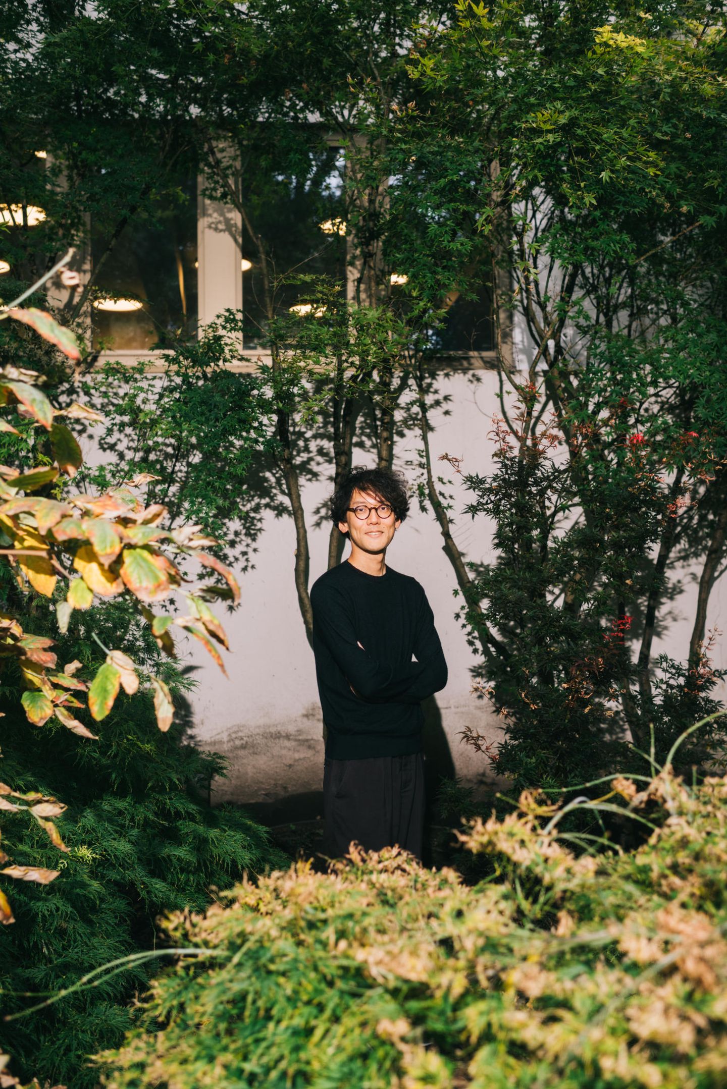 Kohai Saito steht an einen Baum gelehnt im Garten