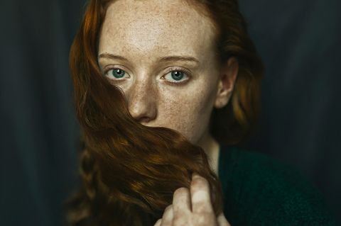Frau bedeckt ihren Mund mit einer Haarsträhne