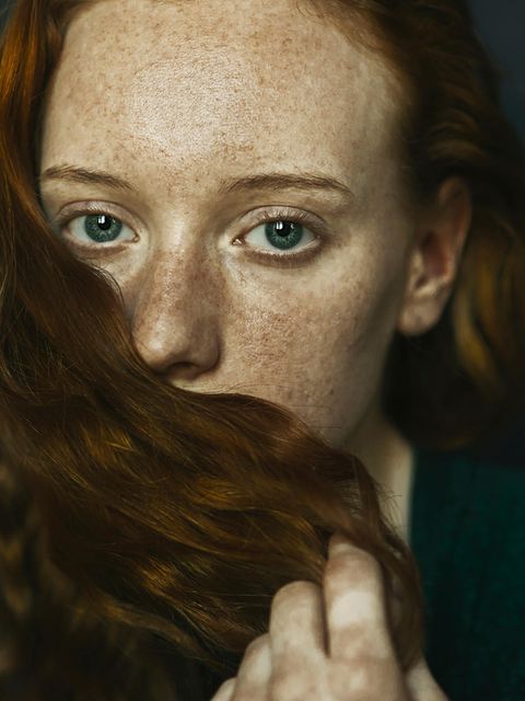 Frau bedeckt ihren Mund mit einer Haarsträhne