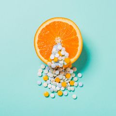 Aufgeschnittene Orange mit Tabletten im Vordergrund