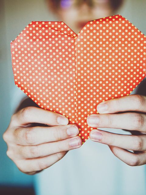 Ein KInd hält ein rotes Origami Herz hoch