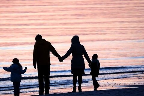 Eltern stehen mit zwei Kindern am Meer