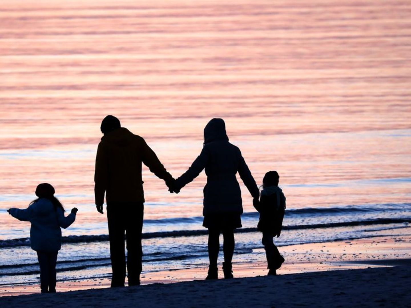 Eltern stehen mit zwei Kindern am Meer