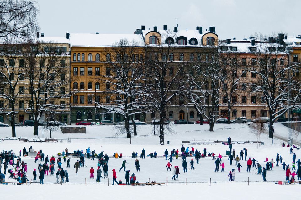 Eisfläche mit Schlittschuhfahrern, dahinter alte Häuser 1.5059