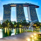 Ein Steg auf den Dragonfly Lake bei Nacht mit vielen Lichtern und moderner Architektur im HIntergrund