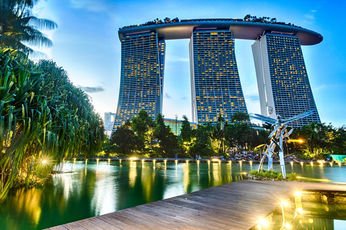 Ein Steg auf den Dragonfly Lake bei Nacht mit vielen Lichtern und moderner Architektur im HIntergrund