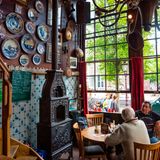 gemütliches Café mit hohen Fesntern und Delft-Tellern an den Wänden