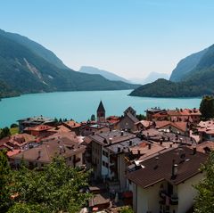 Blick auf das am Molvenosee gelegene Dorf Andalo. Italienische Häuser im Vordergrund, der See erstreckt sich im Hintergrund.