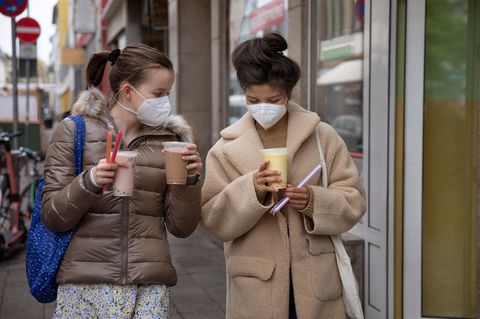 zwei Mädchen mit Maske und To-Go Getränken