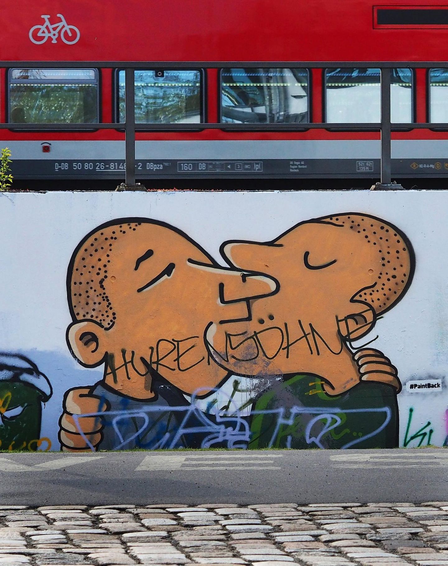 Schriftzug "Hurensöhne" prangt auf einem Graffiti, das küssende Männer zeigt