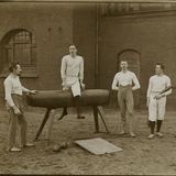 Vier Turner vor einem Backsteingebäude, einer von ihnen sitzt auf einem Seitpferd