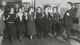 Ein Mann im schwarzen Anzug macht einer Gruppe schwarz gekleideter Frauen Bewegungen vor